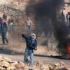 Warga Palestina melemparkan batu ke arah polisi antihuru-hara Israel di desa Hizme di Yerusalem Utara , pada t